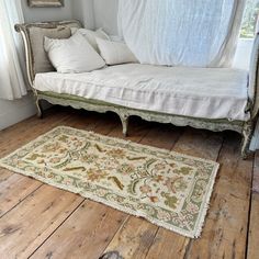 a white day bed sitting on top of a wooden floor next to a large rug