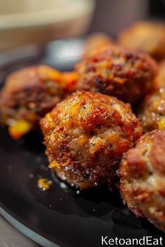 cooked meatballs on a black plate with ketchup and mustard sprinkles