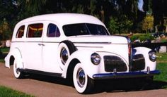 an old white car is parked on the side of the road