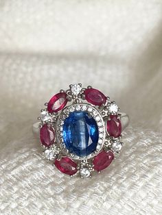 Beautiful vintage look oval top rich blue Nepal kyanite, red ruby and cubic zirconia ring.  14K white gold plated over 925 sterling silver US size: 8 Stones: 8.7 x 7mm; 4 x 3mm and 2mm Face ring: 19.5 x 17.5 mm R743 Oval Multi-stone Ruby Ring, Oval Multi-stone Sapphire Gemstones, Oval Sapphire Gemstone With Multi-stone Detail, Oval Multi-stone Ruby Ring In White Gold, Dazzling Oval Sapphire Gemstones, Oval Sapphire Multi-stone Gemstones, Dazzling Oval Ruby Ring For Anniversary, Oval Sapphire Gemstone With Halo Setting, Red Multi-stone Sapphire Ring