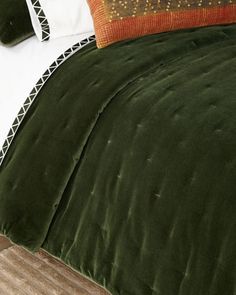 a bed with green velvet comforter and pillows