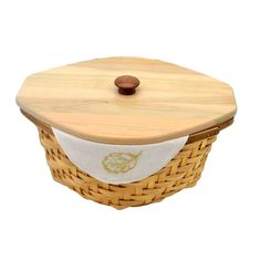 a wooden basket with a white cloth on it and a brown button in the lid