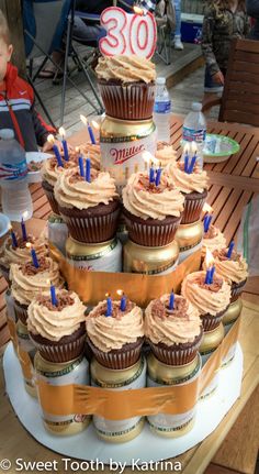 cupcakes are stacked on top of each other in front of a birthday cake