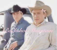 two men sitting in the back of a pick up truck with hats on their heads