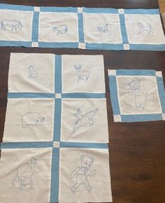 four pieces of cloth with blue and white drawings on them sitting on a wooden table