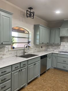 a kitchen with gray cabinets and marble counter tops