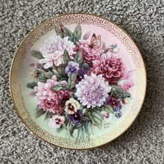 a plate with flowers painted on it sitting on the floor next to a carpeted area