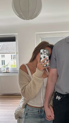 a woman is taking a selfie with her cell phone while standing next to a man