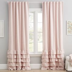 a pink curtain with ruffled edges in front of a white chair and pictures on the wall