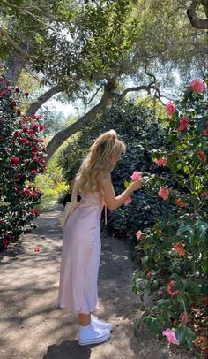 a woman in a pink dress looking at flowers