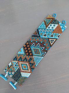 a blue and brown beaded bracelet sitting on top of a wooden table next to a pair of scissors