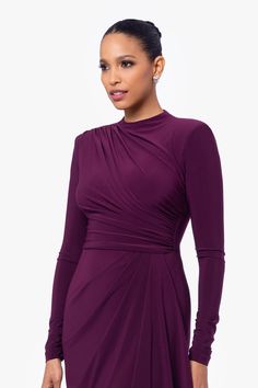 a woman wearing a purple dress with long sleeves and an asymmetrical neckline