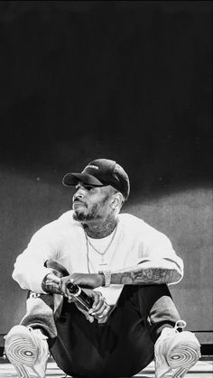 a black and white photo of a man sitting on the ground holding a baseball bat