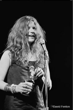 a woman with long hair standing in front of a microphone and smiling at the camera