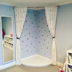 a child's bedroom decorated in blue and white with stars on the wall, along with toys