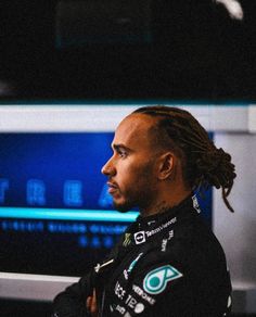 a man with dreadlocks sitting in front of a computer monitor and looking off to the side