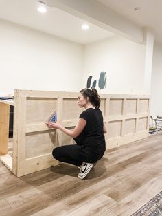 a woman sitting on the floor with a piece of wood