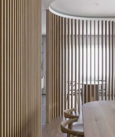 a wooden table sitting in front of a wall with vertical slatted panels on it