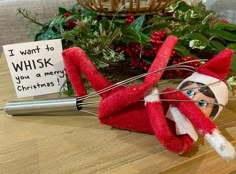 an elf is holding a whisk in front of a christmas card on a table