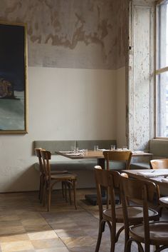 an empty restaurant with tables and chairs in front of a large painting on the wall