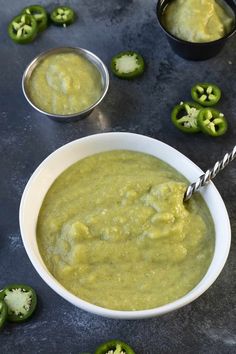 a white bowl filled with green soup next to some peppers