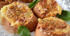 four baked potatoes with cheese and herbs on foil