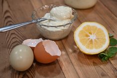 an egg, orange and yogurt sit on a wooden table with other ingredients