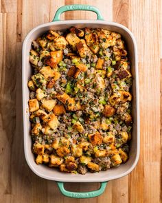 a casserole dish filled with stuffing and vegetables on a wooden counter top, ready to be eaten