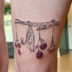 a woman's leg with tattoos on her legs and flowers hanging from the bars