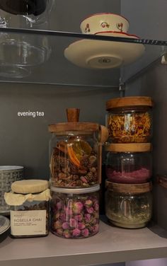 the shelves are filled with different types of teas and other things in glass containers