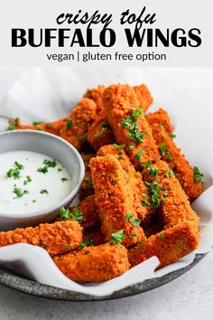 a bowl filled with fried food next to a small cup of ranch dressing on the side