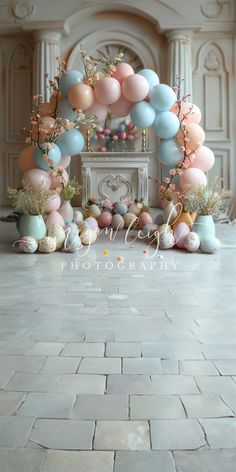 an arch made out of balloons with flowers and other decorations on the floor in front of a fireplace