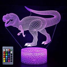 an illuminated dinosaur lamp with remote control and color changing lights on the table next to it