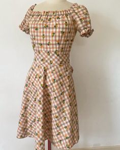 A simple, vintage cottage dress unlabeled and lovingly hand made & « home made » ! How charming and rustic this cotton fabric is, right 🌷 ? Brown tartan with bouquet of tulips. It was likely made around the 1970s.  As stated, if you look closely at the seams, they aren't as regular and straight as machine ; the seams are all carefully made by hand. There are working elastics around the sleeves and collar. A large belt attacked to the dress to enhance the fit like in the earlier decades. It clos Fitted Gingham Dress With Floral Print, Fitted Plaid Vintage Dress, Retro Cotton Vintage Dress For Picnic, Retro Gingham Cotton Vintage Dress, Retro Gingham Vintage Dress In Cotton, Retro Gingham Vintage Cotton Dress, Vintage Gingham Cotton Dress, Vintage Gingham Dress For Garden Party, Brown Cotton Cottagecore Dress