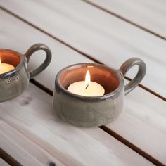 two tea lights sitting on top of a wooden table