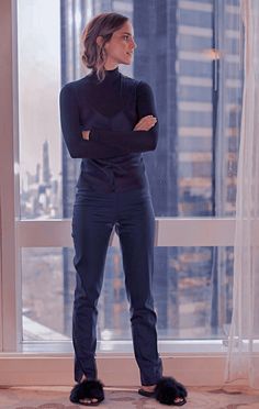 a woman standing in front of a window with her arms crossed