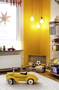 a yellow toy car sitting on top of a white rug in front of a window