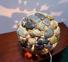 a lamp made out of rocks on top of a wooden table next to a wall