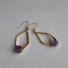 A faceted Amethyst bead set in a double sided diamond shaped frame creates demure drop earrings. 8mm faceted amethyst bead gold plated brass double sided diamond shaped bail gold plated brass french ear wires drop: 2" width: 3/4" Handmade in Lincoln, Nebraska Diamond-shaped Pierced Jewelry Gift, Nickel-free Diamond-shaped Jewelry For Gifts, Nickel-free Diamond-shaped Jewelry Gift, Faceted Dangle Jewelry For Everyday Wear, Everyday Dangle Faceted Jewelry, Faceted 14k Gold Filled Yellow Gold Earrings, Elegant Everyday Diamond-shaped Jewelry, Purple Metal Drop Earrings, Gold Faceted 14k Gold-filled Earrings