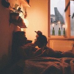 two people laying in bed looking out the window