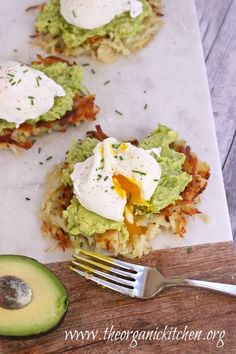 an avocado and egg sandwich on a cutting board next to a knife and fork