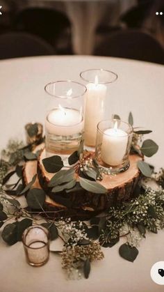 candles and greenery are arranged on a wood slice