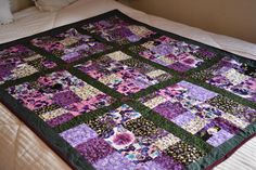 a purple and green quilt on top of a bed