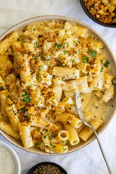 a bowl filled with pasta and sauce on top of a white table next to other bowls