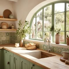 a kitchen with an arched window, sink and green cupboards on the countertop