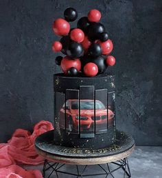 a black cake with red and black balloons on top