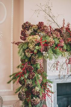 a fireplace decorated with greenery and red berries