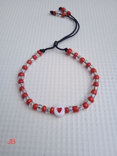 a red and white beaded bracelet with a heart