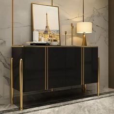 a black and gold sideboard in a room with a painting on the wall next to it