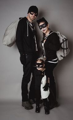 the man and woman are dressed up in costumes with masks on their faces, standing next to each other